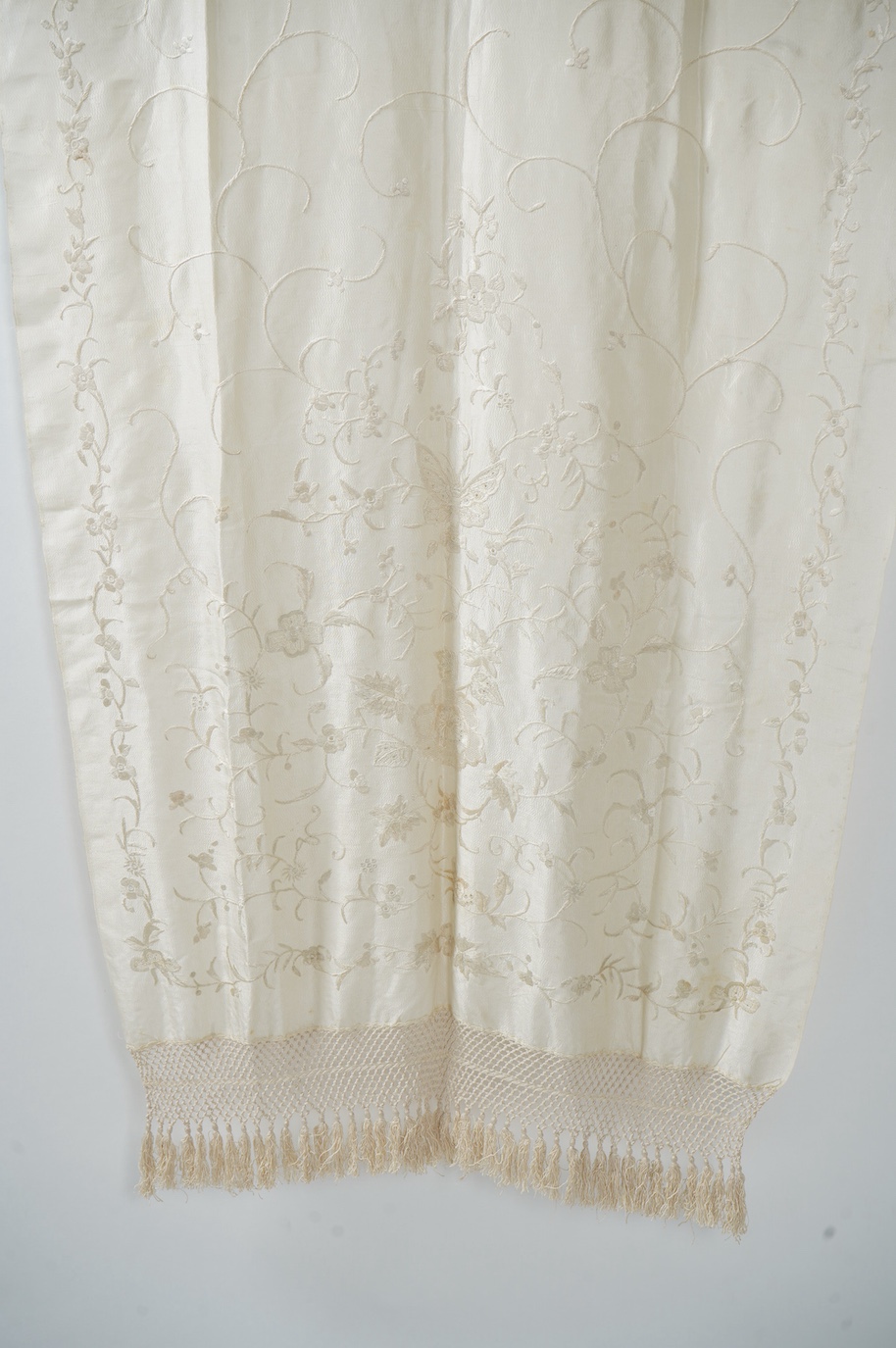 An early 20th century Chinese cream on cream silk embroidered, fringed stole, 65cm wide. Condition - some light staining.
